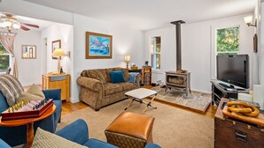 A living room with a sofa, a coffee table, a fireplace, a television, and a chessboard. - Vineyard Views + Two Porches | Willow Creek AVA | Dunning Ranch Guest Suite Two (Paso Robles)