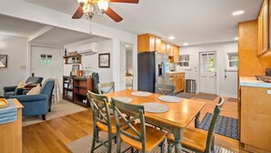A modern kitchen with wooden cabinets, a stainless steel refrigerator, and a dining area with a wooden table and chairs. - Vineyard Views + Two Porches | Willow Creek AVA | Dunning Ranch Guest Suite Two (Paso Robles)