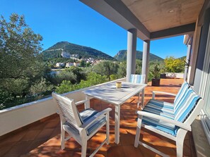 A terrace with a table and chairs, a view of a mountain and village, and a potted plant. - Waterfront Oasis by Interhome (Ston)