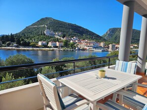 A balcony with a table and chairs overlooking a lake, with buildings and hills in the background. - Waterfront Oasis by Interhome (Ston)