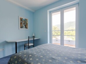 Una camera da letto con un letto, una scrivania, una sedia, una finestra e un quadro appeso al muro.