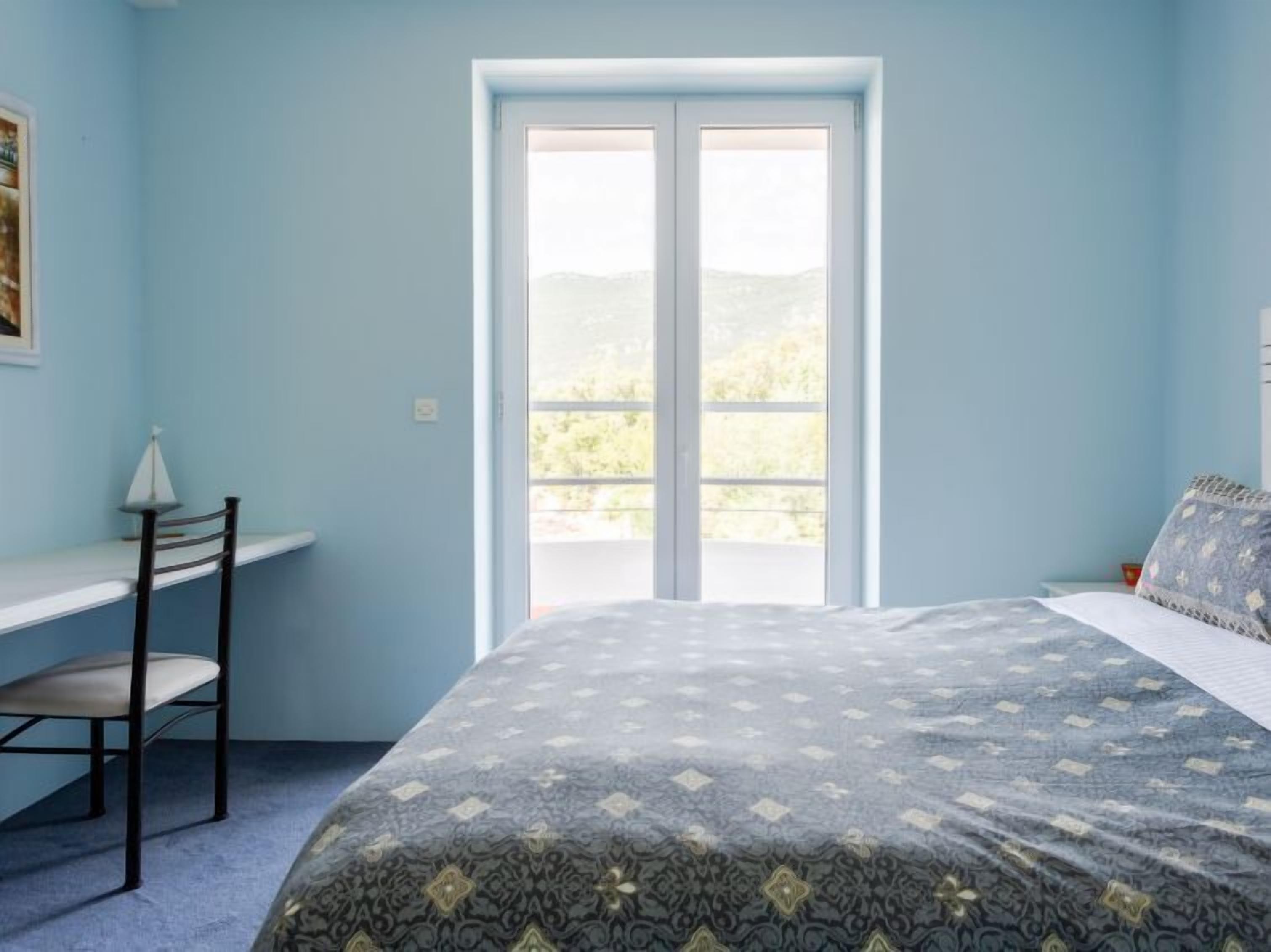 Een slaapkamer met een bed, een bureau en een stoel.