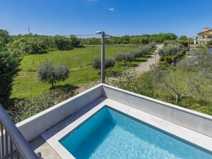 Una piscina rectangular con superficie de agua cristalina y azul, rodeada por una solana de concreto.