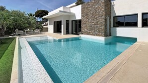 Et moderne hus med swimmingpool, stenfassade og balkon.