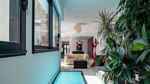 Et moderne interiør med en pool, en sofa og frodigt grønt.