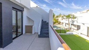 Un immeuble résidentiel moderne doté d’un escalier menant à un balcon, d’une piscine et d’une pelouse bien entretenue.