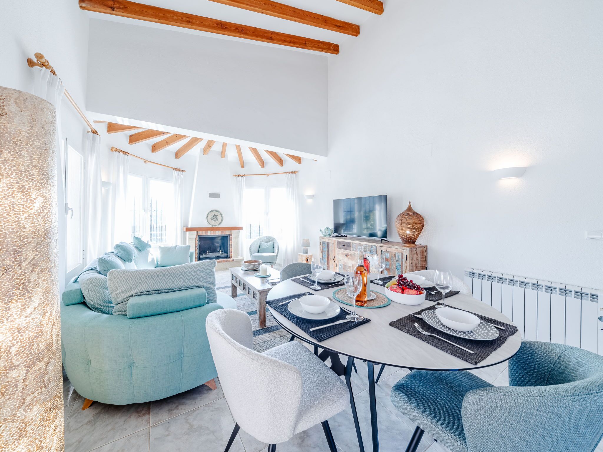 Una sala de estar moderna con comedor, que incluye un sofá, sillas, un televisor y una chimenea.