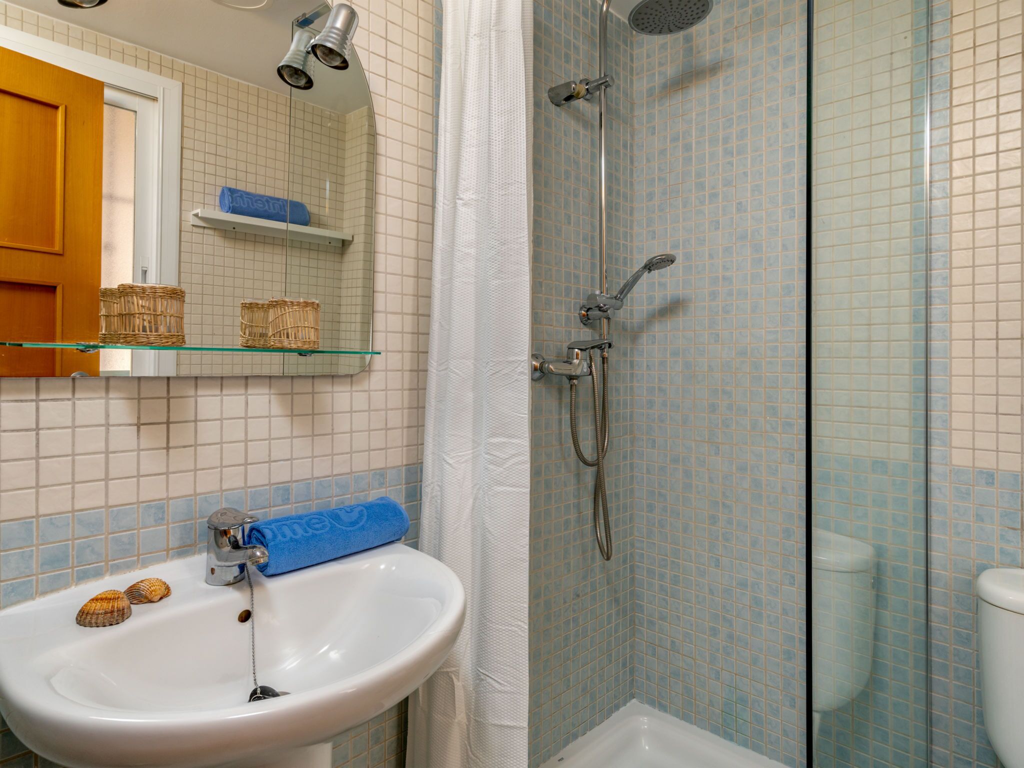 A bathroom with a sink, mirror, and shower.