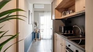 A modern kitchen with wooden cabinets, a stainless steel sink, and a built-in oven. - Vinnies Homes (Heraklion)