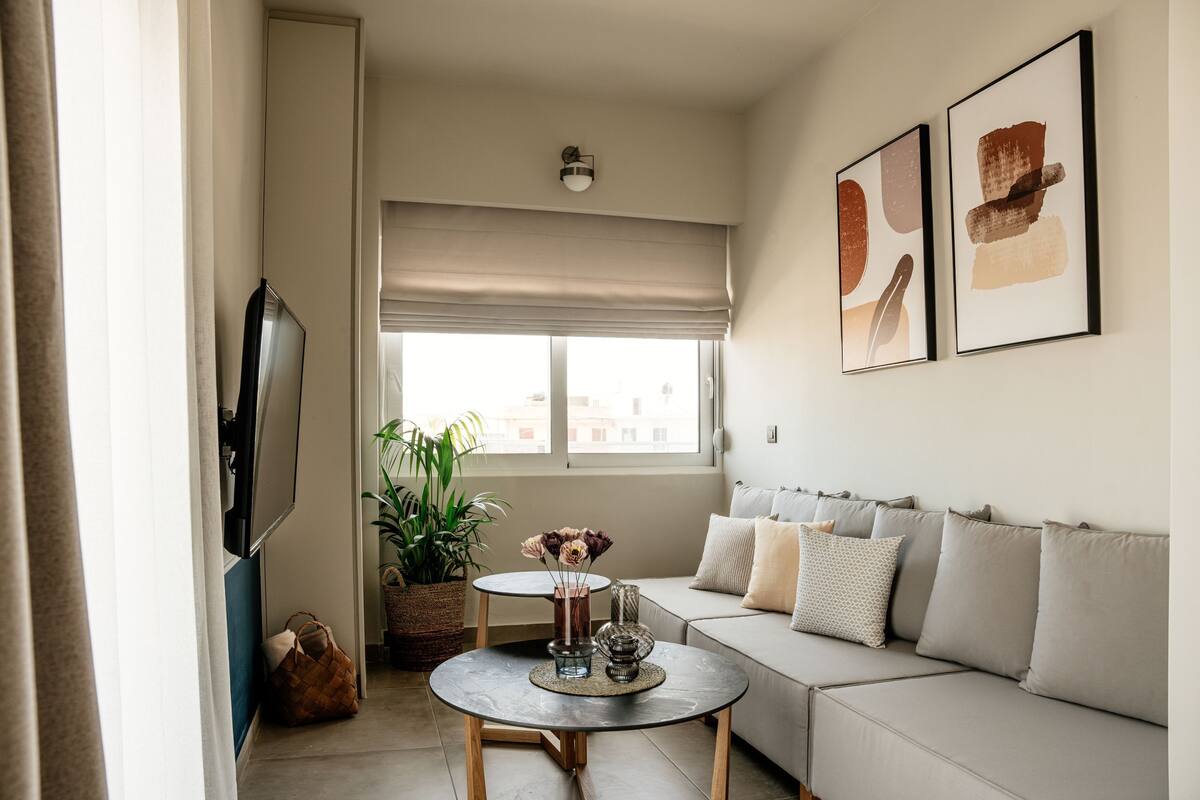 Una sala de estar con sofá, mesa de centro, televisor y obras de arte en la pared.