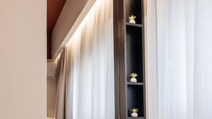 A bathroom with a mirror, a vanity with a black shelf, and a round stool. - Vinnies Homes (Heraklion)