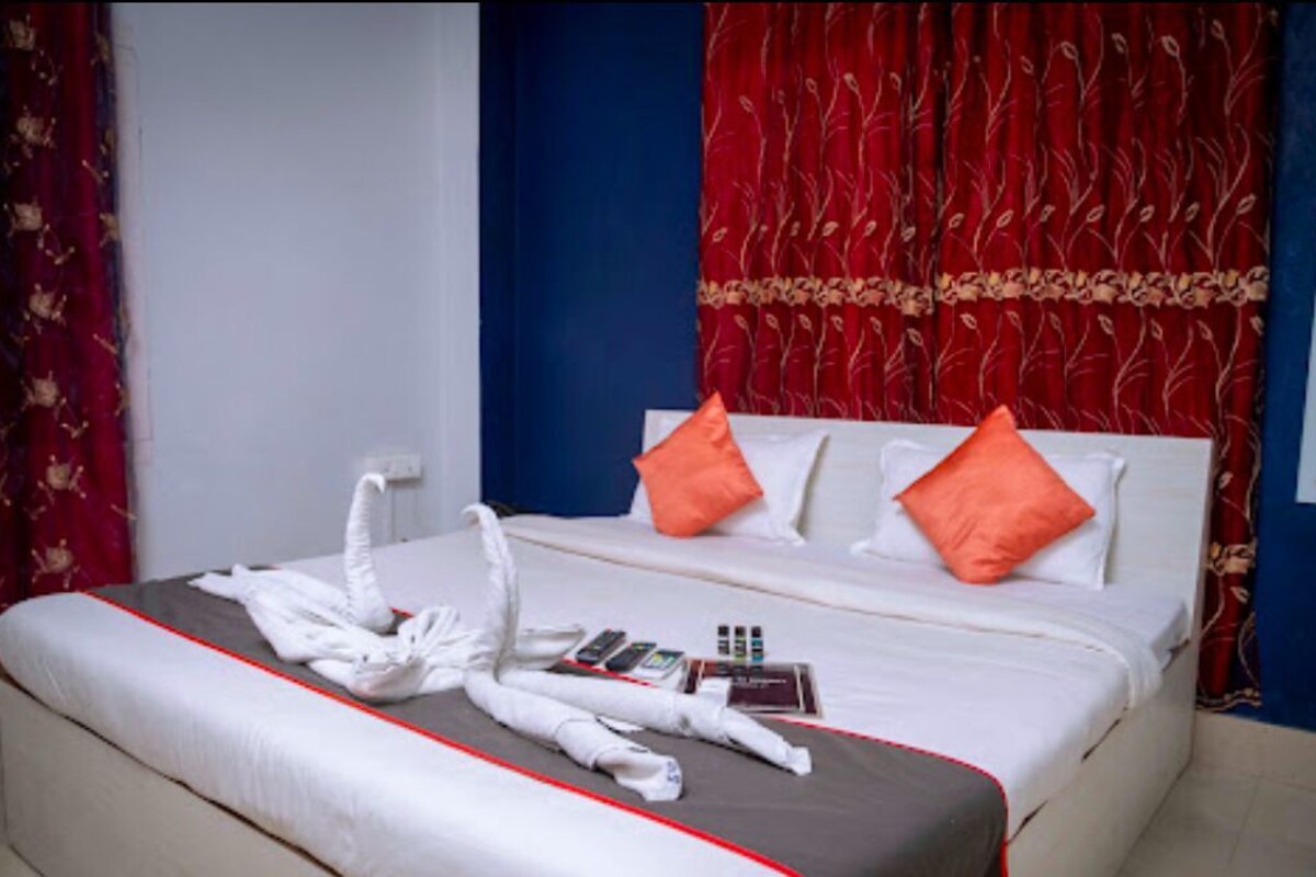 A hotel room with a bed, pillows, a blanket, and a towel arrangement.