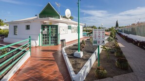 A small white building with a green roof and a satellite dish.