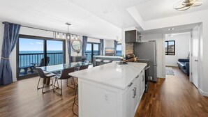 Une cuisine moderne dotée d’un grand îlot central, d’un coin repas offrant une vue agréable et d’un balcon avec vue.