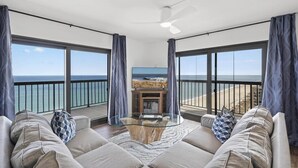 Un balcon spacieux avec une table basse en verre, un canapé et un téléviseur à écran plat.