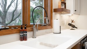 A modern bathroom with a wooden vanity, a large window, and a view of trees.
