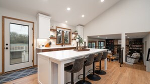 A spacious kitchen with a large island, bar stools, and a view of the outdoors.