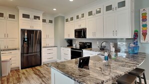 A modern kitchen with white cabinetry, stainless steel appliances, and a granite countertop. - Driftwood | Canal Front, Sound View, Private Dock! (Topsail Beach)