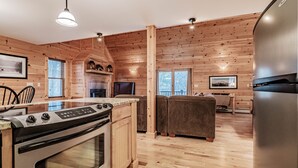 Una cocina moderna con paredes de madera, horno empotrado, zona de comedor con mesa y sillas, y un rincón de estar con sofá.