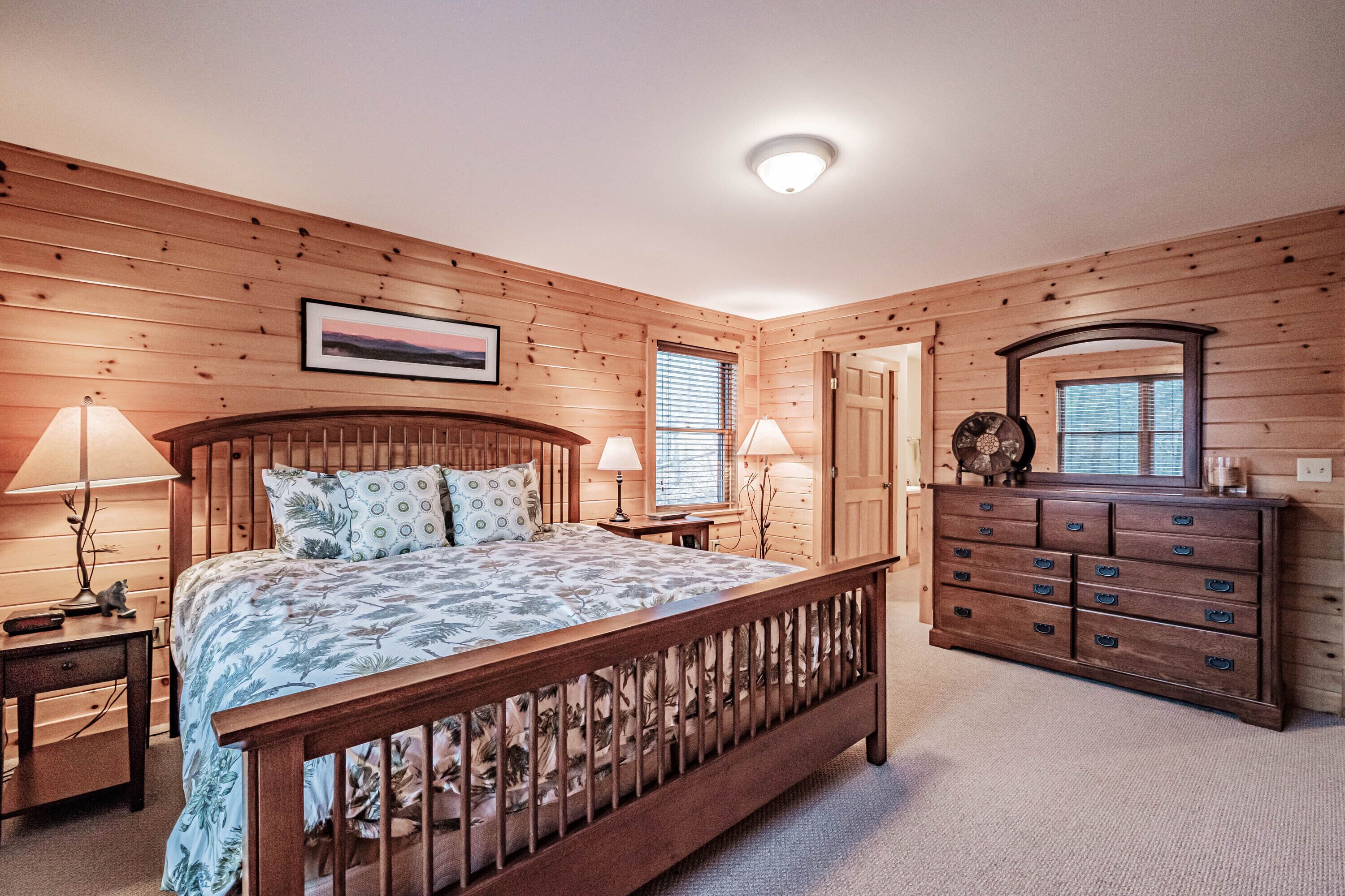 A bedroom with a wooden bed, a dresser, and a nightstand.