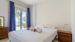 A hotel room with a bed, a wooden nightstand, and a window with curtains. - Elegant Mijas Costa Holiday Home for 4 (Mijas Costa)