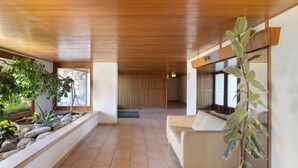 Un interior moderno con techo de madera, sofá beige y plantas en macetas.
