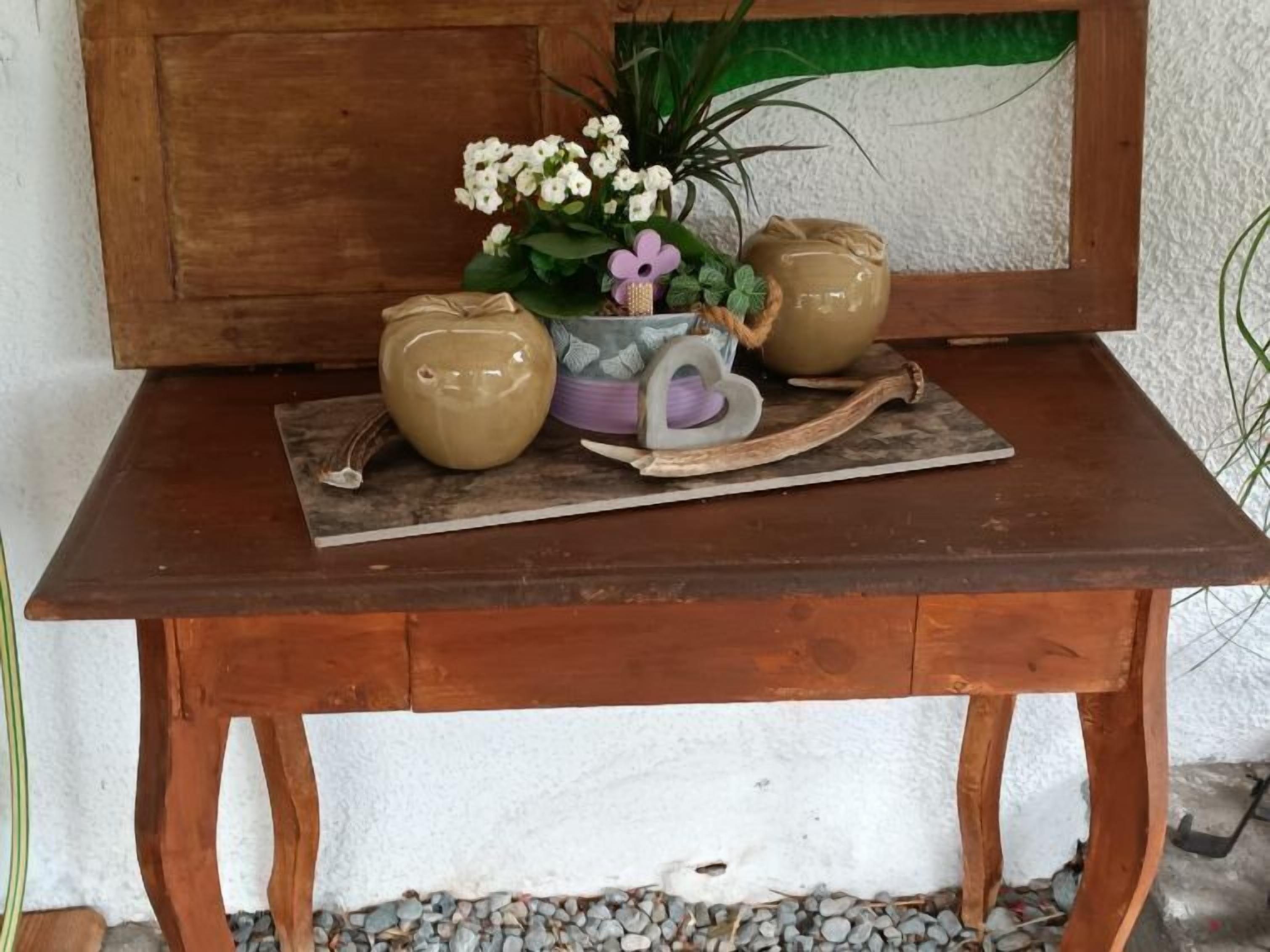 Una taula de fusta amb un ram de flors blanques, una tassa morada i dues testos de ceràmica.