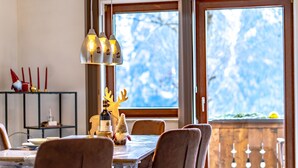 A dining area with a table, chairs, a bottle of wine, and a reindeer decoration. - Ferienwohnung Plattner by Interhome (Ötz)