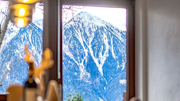 A dining area with a view of snow-covered mountains through a window. - Ferienwohnung Plattner by Interhome (Ötz)