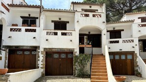 A traditional building with a stone courtyard, wooden doors, and a staircase leading to an upper level. - Very cosy Townhouse 5 minutes walking to the beach  (Pals)