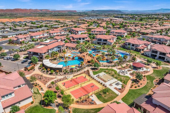 Un barrio residencial con varias casas, una piscina central y una cancha de tenis.
