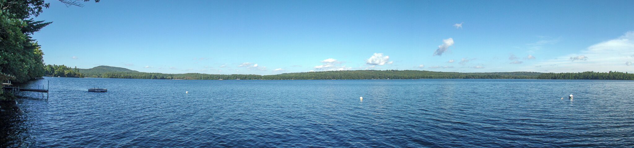 A calm lake with a dock and a small boat.