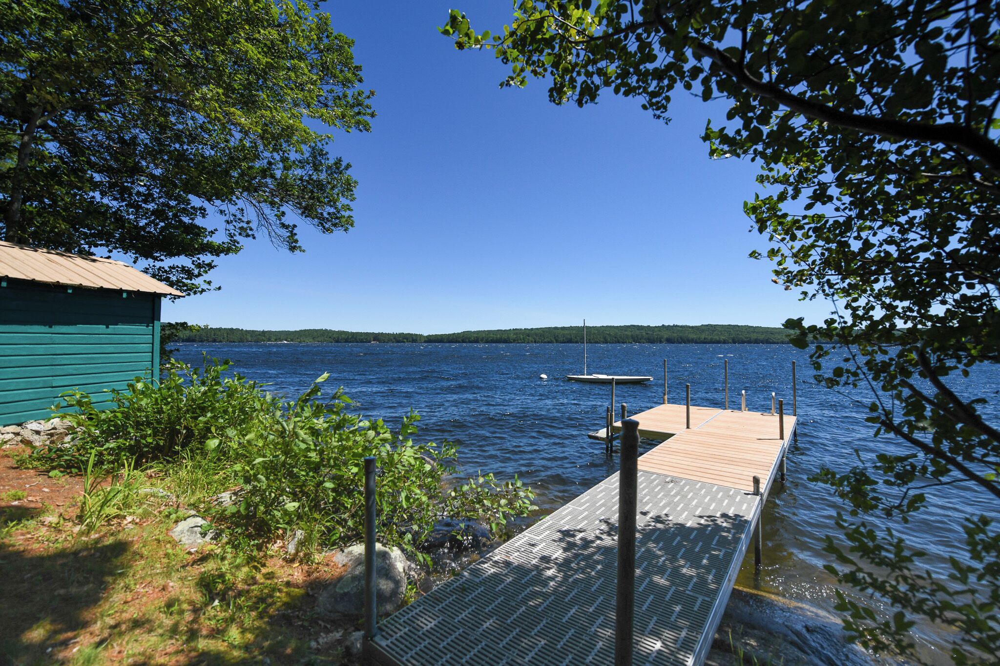 A dock extending into a calm lake with a clear sky.