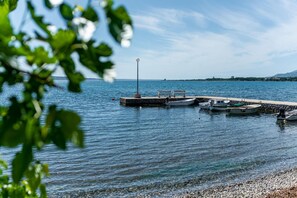 Ein ruhiger See mit Steg, Booten und einer Laterne.