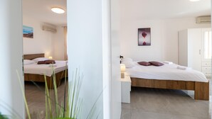 Une chambre à coucher moderne avec un lit en bois, du linge de lit blanc et une table de chevet avec une lampe.