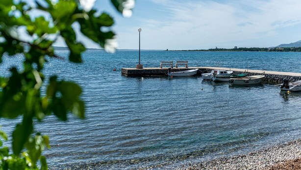 Un lac paisible avec un quai, des bateaux et un lampadaire.