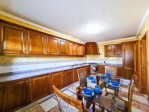 A kitchen with wooden cabinets, a glass dining table, and a built-in oven. - FLH Quinta das Salinas Triplex with Balcony (Vale do Lobo)