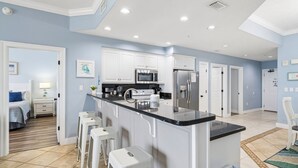 A modern kitchen with white cabinets, a black countertop, and a stainless steel refrigerator.