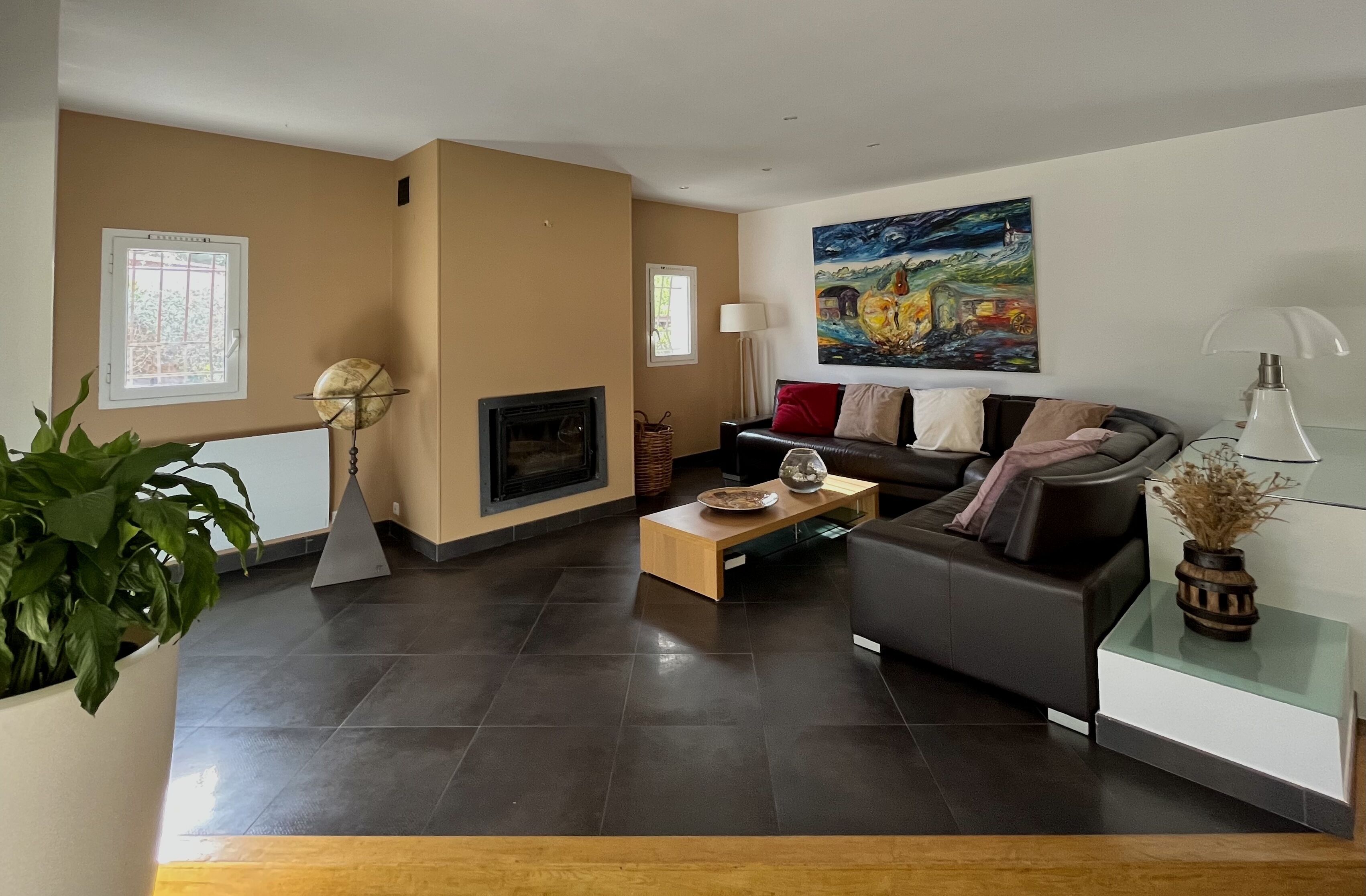 A modern living room with a fireplace, a sofa, a coffee table, and a painting on the wall.