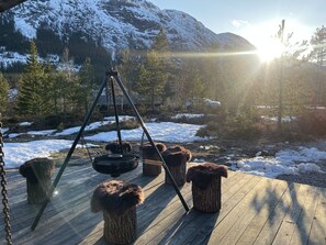 A wooden deck with a hanging chair and a tripod, surrounded by snow-covered ground and trees, with mountains in the background. - Peaceful cabin close to Bø and Lifjell (Vestfold og Telemark)