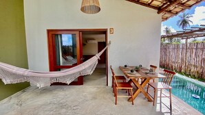 A room with a dining table and chairs, a hammock, and a pool. - Jubaia Milagres by ER (São Miguel dos Milagres)