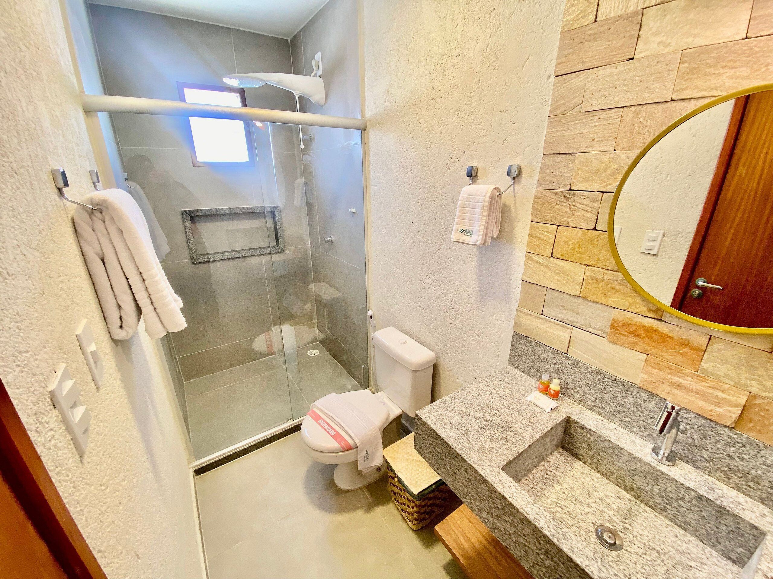 Ein modernes Badezimmer mit einer Duschkabine aus Glas, einer Toilette und einem Waschbecken aus Granit.