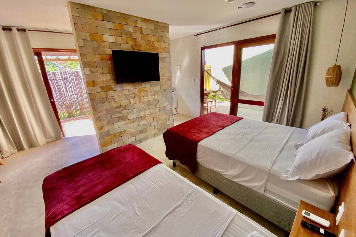Ein Hotelzimmer mit zwei Betten, einer Steinwand, einem Fernseher und einem Balkon mit Blick.