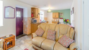 A cozy living room with a leather sofa, wooden side tables, and a kitchen in the background. - The Granary - UK43951 (Lingdale, near Saltburn-by-the-Sea)