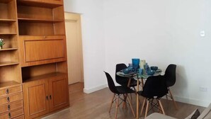 Ein Essbereich mit einem Holzschrank, einem Tisch mit Stühlen und einer kleinen Pflanze auf dem Schrank.