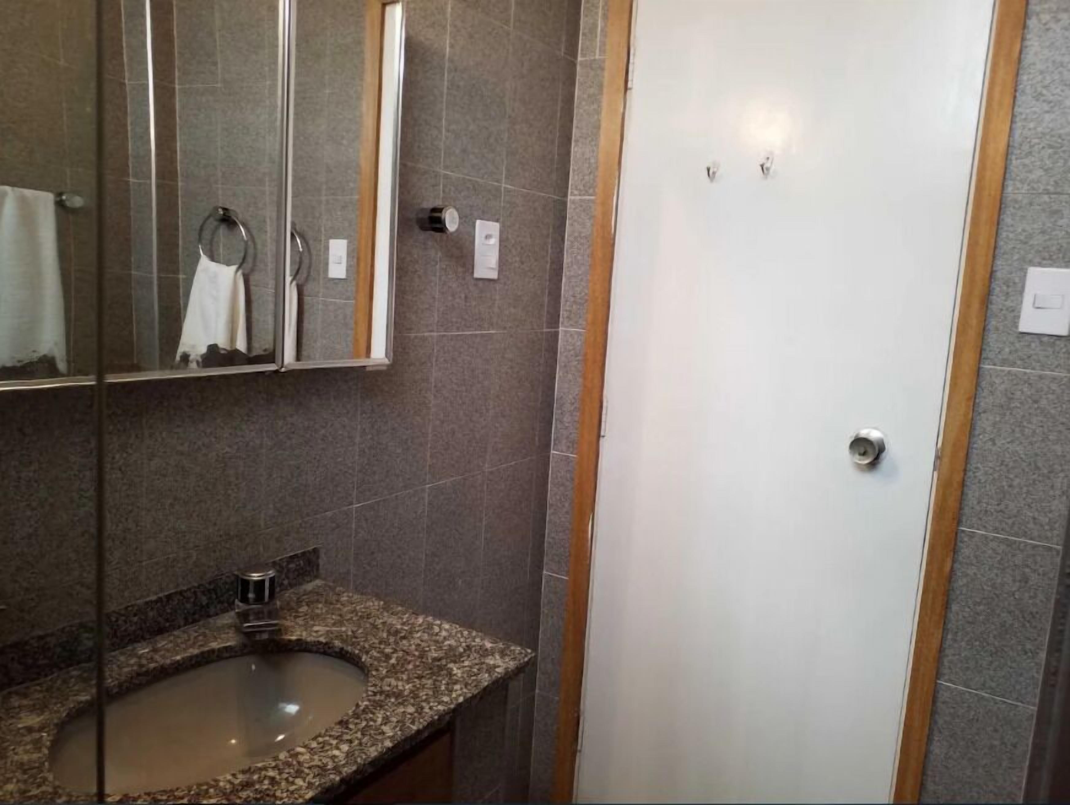 A bathroom with a granite sink, a mirror, and a shower area.