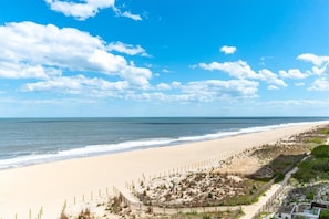 Une vue sur la plage avec une clôture, un sentier et un bâtiment au premier plan.