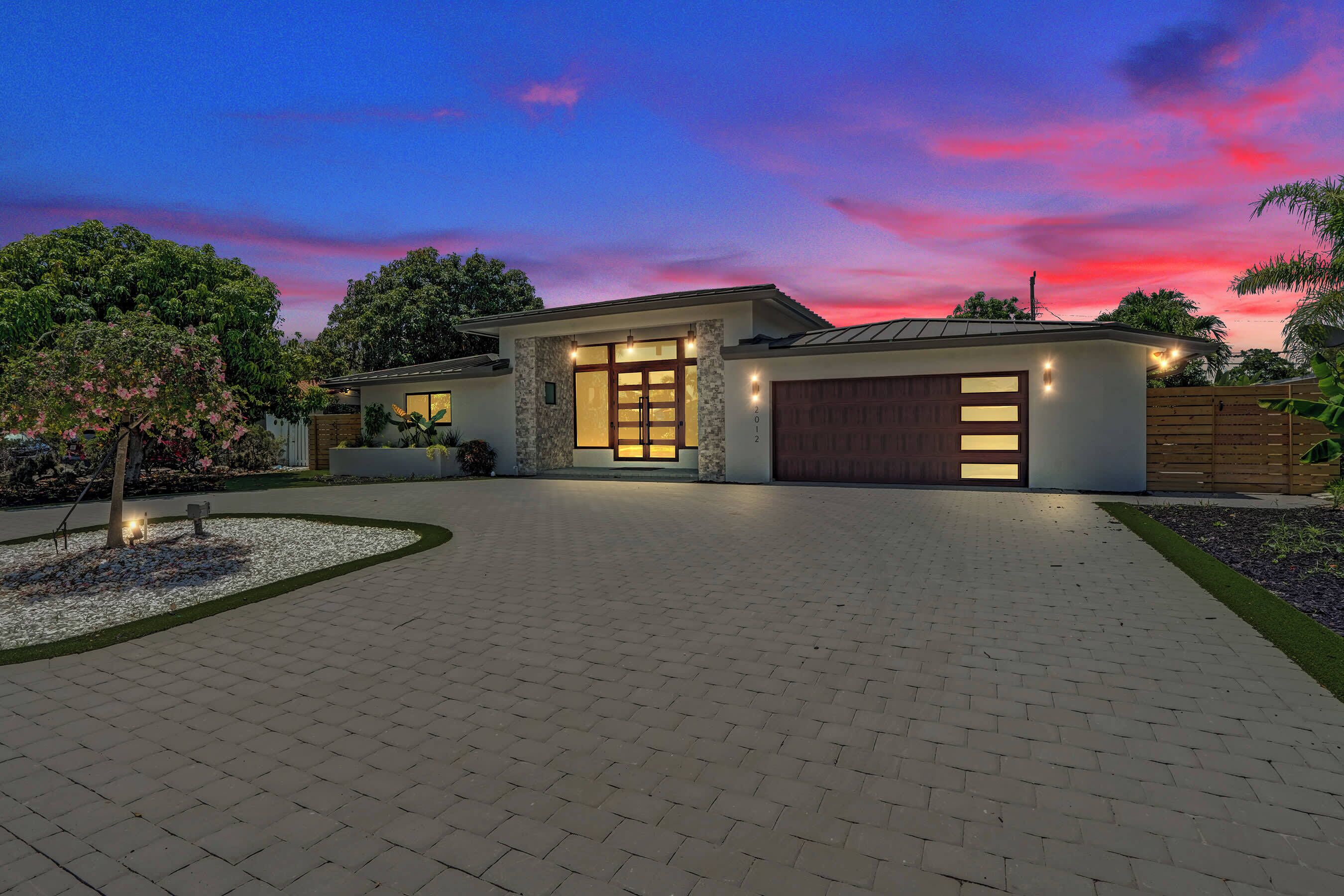 A modern house with a paved driveway, a garage, and a well-lit entrance.