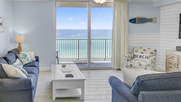 A living room with a view of the ocean, a white coffee table, and a sofa with decorative pillows. - 1bd/2ba Unit w/ a Bunk Alcove and Amazing Views Right on the Gulf! (Panama City Beach)