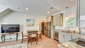 A modern kitchen with a dining area, a TV, and a large window with blinds. - < 1/2 Mi to Old Town: Cozy Bluffton Getaway (Bluffton)